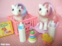 two little pony toys sitting on top of a pink table