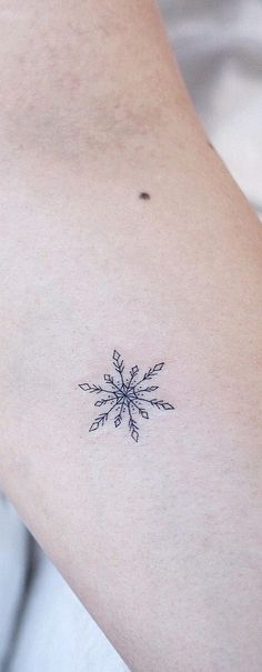 a small snowflake tattoo on the right side of the arm is shown in black ink