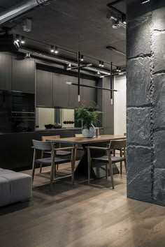 a dining room table with chairs and a couch in front of an exposed stone wall