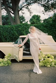 a woman in a wedding dress standing next to a car