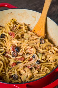 a red pan filled with pasta and olives