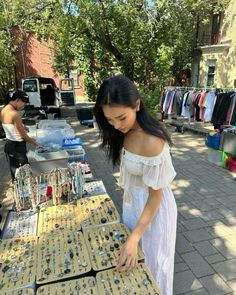 a woman standing over a table with lots of jewelry on it