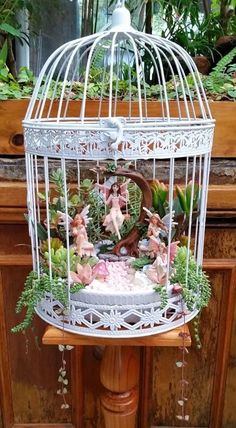 a white birdcage filled with lots of plants