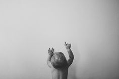 a small child reaching up into the air with their hands in front of a white wall