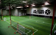 an indoor soccer field with the words the futbol factory on it's wall