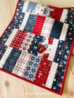 a red, white and blue quilted placemat on a wooden table with scissors