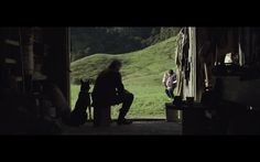 two people and their dogs are sitting in the doorway to an open barn with mountains in the background