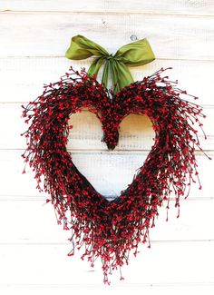 a heart shaped wreath with red berries hanging from it