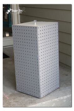 a white box sitting on the side of a house next to a door with holes in it