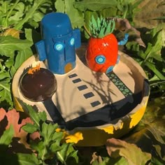 a toy carrot and some other items on a plate in the grass with leaves around it