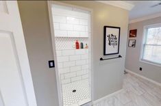 a bathroom with a shower and tiled flooring next to a white door in the wall