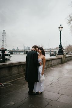 Couple standing by river Thames in London over looking the London Eye. Wedding Table Details, City Hall Wedding