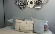 a bed with pillows and decorative plates hanging on the wall above it's headboard