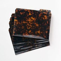 five square coasters in tortoise shell pattern on white background with black edges