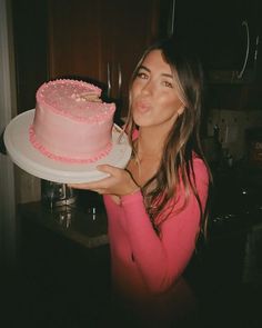 a woman holding a pink cake on top of a white plate