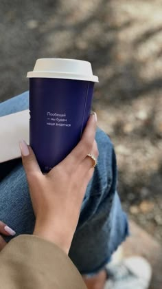 a woman is holding a coffee cup in her hand and reading the book she has written on it