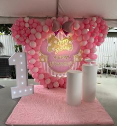 a pink and white birthday decoration with balloons