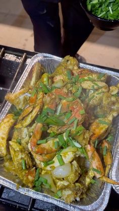 a pan filled with food sitting on top of a metal tray next to a bowl of greens