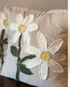 two white flowers are embroidered onto the back of a pillow