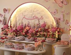 there are many desserts on the table with pink flowers and butterflies around them,