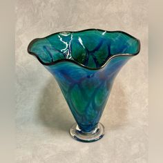 a blue and green glass vase sitting on top of a white tablecloth covered floor