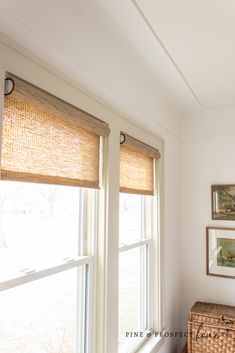 a bedroom with two windows and wicker baskets on the floor