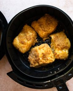 four pieces of fried food cooking in an air fryer basket on a counter top