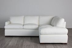 a white leather sectional sofa with chaise lounge in the corner on a wood floor