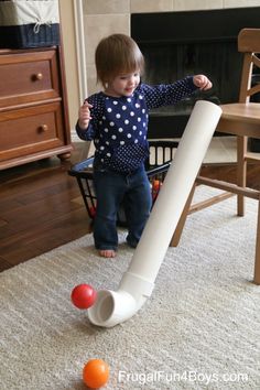 a toddler playing with an inflatable ball and tee on the floor next to a fireplace