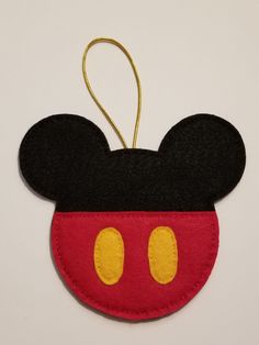 a mickey mouse ornament hanging on a white wall with a red and black face