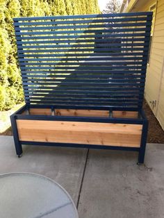 a wooden bench sitting on top of a cement ground next to a tree and bushes