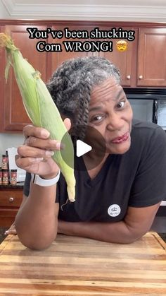 an older woman holding up a corn on the cob in her kitchen with text that reads, you've been shucking corn wrong