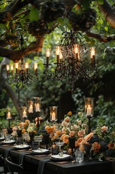 an outdoor dining table with candles and flowers on it, surrounded by lush greenery