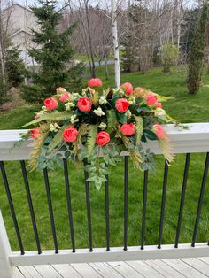 a bunch of flowers sitting on top of a white rail next to grass and trees