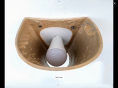 a white light bulb in a brown bowl on the side of a wall mounted fixture