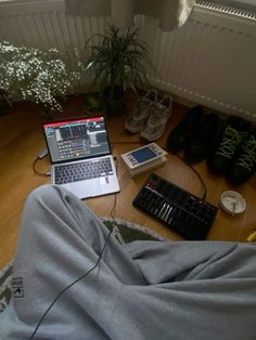 an open laptop computer sitting on top of a wooden floor next to a pair of shoes