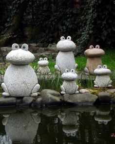 the frog statues are sitting on top of the rocks by the water's edge