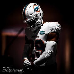 a miami dolphins football player wearing a white uniform and holding his hands in his pockets