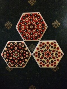 three hexagonal beaded coasters sitting on top of a table