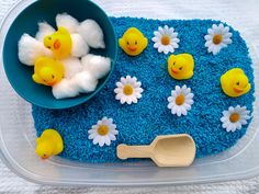 a plastic container filled with blue stuff and rubber ducky toys on top of it