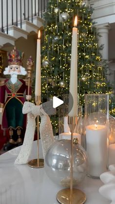 a table topped with candles next to a christmas tree and santa clause in the background