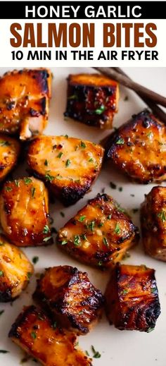 grilled honey garlic salmon bites on a white plate with chopsticks and parsley