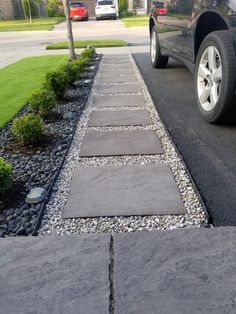 a car parked on the side of a road next to a graveled driveway area