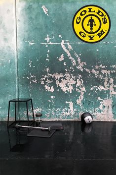 a black chair sitting in front of a green wall with a yellow logo on it