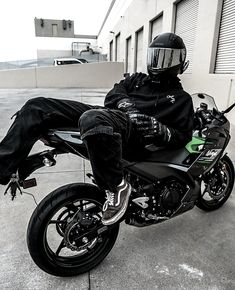 a man sitting on the back of a motorcycle in front of a building with his feet up