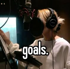 a person wearing headphones reading a book in front of a microphone with the words goals written on it