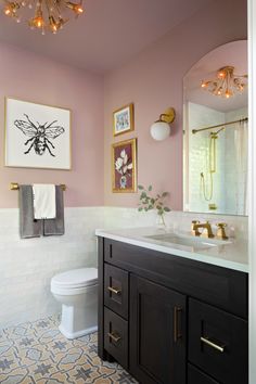 a bathroom with pink walls, gold fixtures and pictures on the wall above the toilet