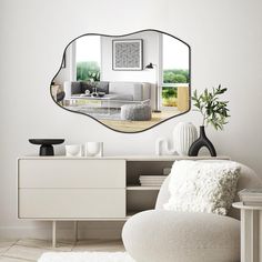 a living room with white furniture and a large mirror on the wall above it's sideboard