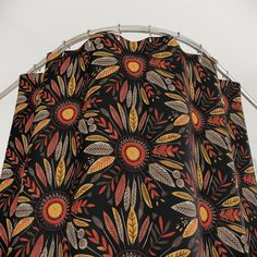 a black shower curtain with an orange and yellow flower design on it's side