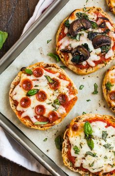 four mini pizzas on a baking sheet